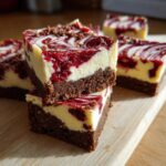 Close-up of stacked Christmas cheesecake bars with a rich chocolate base and red berry swirls.