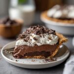 A slice of rich Christmas chocolate pie topped with whipped cream and chocolate shavings.