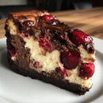 A rich slice of Cranberry Fudge Cheesecake with chocolate layers, creamy filling, and whole cranberries.