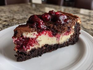 A slice of rich cranberry fudge cheesecake with layers of chocolate crust, cheesecake filling, and cranberry topping.