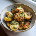 A bowl of roasted garlic butter potatoes, halved and sprinkled with fresh parsley.