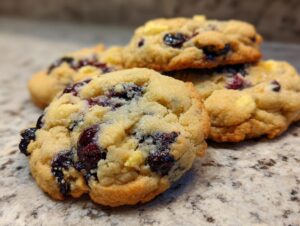 A close-up view of several delicious lemon blueberry cookies, showcasing plump blueberries and golden cookie dough.
