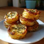 Close-up of golden-brown potato stacks with garlic herb butter and parsley, served on a white plate.