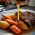 Pouring rich gravy over a tender slow cooker pot roast with hearty carrots and potatoes.