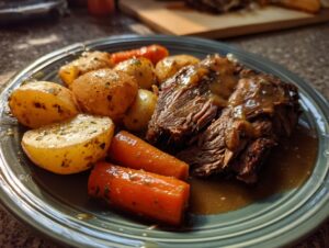 A close-up of a fork-tender slow cooker pot roast served with roasted potatoes and carrots in gravy.