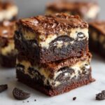 A stack of three decadent Slutty Brownies, showcasing layers of chocolate brownie, cream cheese, and Oreos.