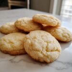 A close-up of a pile of soft sugar cookies, lightly dusted with sugar.
