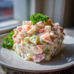 A beautifully molded portion of creamy seafood salad featuring shrimp, celery, and herbs, garnished with fresh parsley.