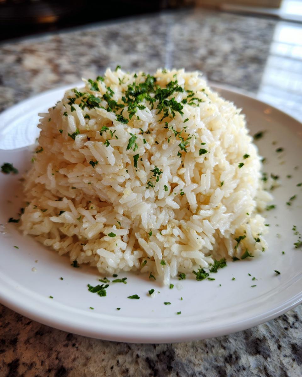A perfectly molded serving of fluffy garlic butter rice topped with fresh chopped parsley.