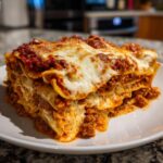 A thick, layered slice of homemade lasagna topped with melted mozzarella cheese and rich meat sauce.