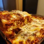 A close-up shot showing a cheesy, saucy slice of lazy lasagna being lifted from the pan, with cheese stretching below.