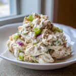 A generous mound of creamy cottage cheese chicken salad mixed with red onion and green onion, served in a white bowl.