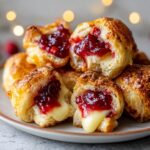 Close-up of warm cranberry brie bites showing melted brie cheese and bright red cranberry filling inside flaky pastry.