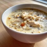 Close-up of a hearty bowl of creamy chicken wild rice soup with visible shredded chicken and grains.