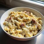 A close-up of creamy kielbasa pasta made with rotini noodles, covered in a rich sauce and topped with shredded cheese.