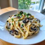 A close-up of creamy fettuccine mushroom pasta topped with sautéed mushrooms and fresh parsley.