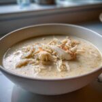 A creamy bowl of homemade she crab soup generously topped with shredded white and orange crab meat.