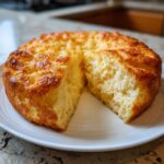 A round loaf of golden brown cloud bread sliced open to show its fluffy, airy interior.