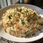 A close-up of a white bowl filled with fluffy rice pilaf recipe, featuring toasted vermicelli and fresh chopped parsley.