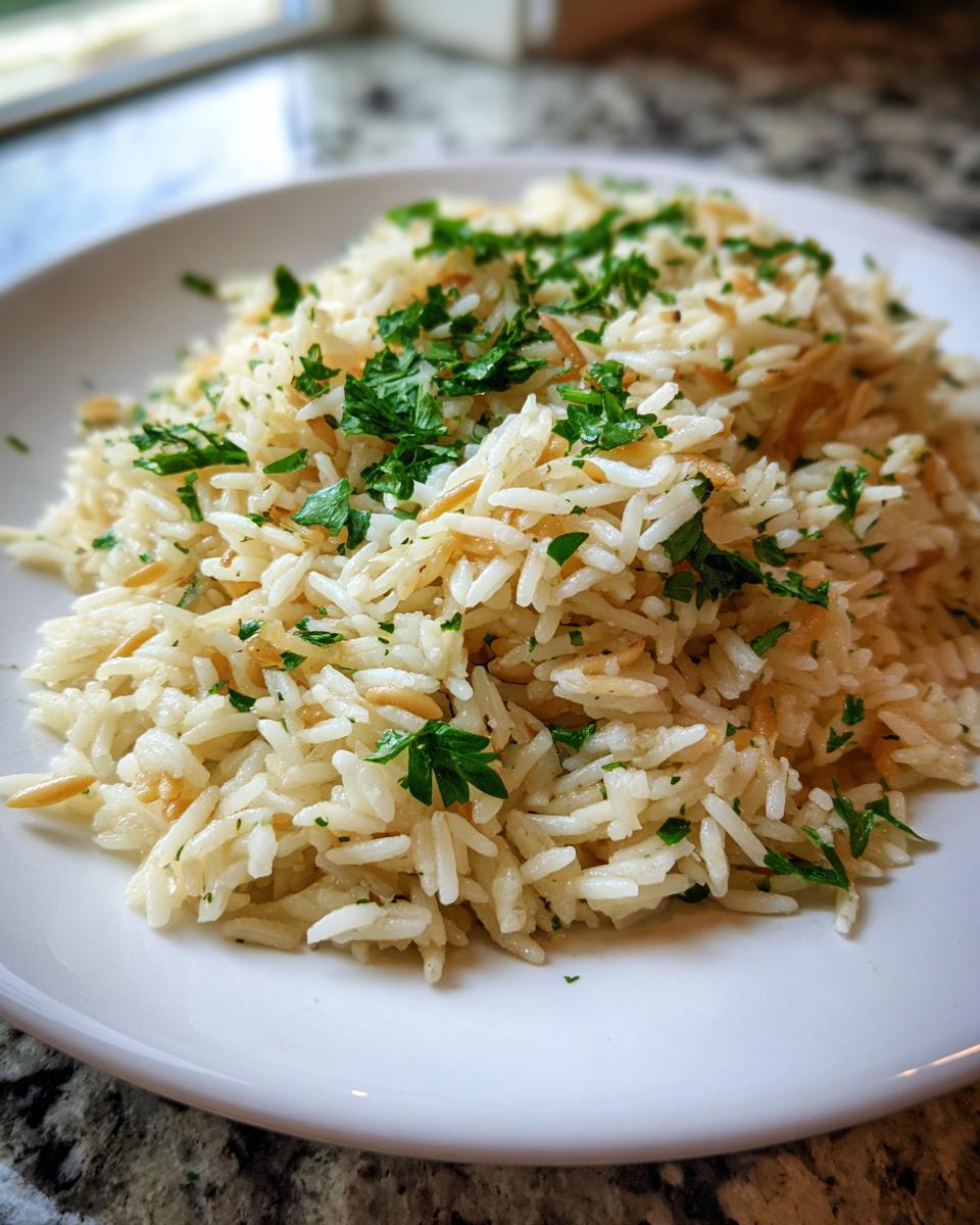 A close-up of a serving of fluffy rice pilaf recipe mixed with toasted vermicelli and topped with fresh chopped parsley.
