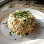 A mound of fluffy garlic butter rice topped generously with fresh chopped parsley on a white plate.