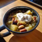 Close-up of a hearty sauerkraut soup bowl topped with a dollop of sour cream and paprika.