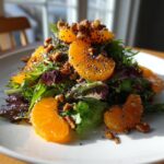 A bright mandarin orange salad featuring mixed greens, bright orange segments, toasted nuts, and poppy seeds.