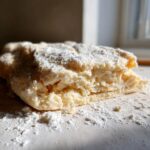 Close-up of raw, flaky butter pie crust dough dusted with flour, showing layers.