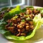 Close-up of delicious chicken lettuce wraps filled with savory ground chicken and mushroom mixture, garnished with green onions.