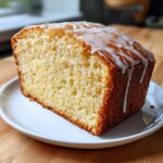 Close-up of a moist slice of cream cheese pound cake with a white sugar glaze drizzled on top.