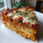 A thick, tall slice of baked spaghetti pie layered with meat sauce and melted mozzarella cheese, garnished with parsley.