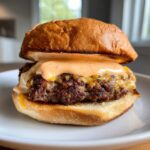Close-up of a juicy smash burger topped with melted cheese and generous drizzle of smash burger sauce.