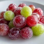 Close-up of red and green candy grapes coated heavily in sparkling sugar crystals.