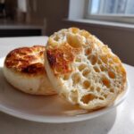 Close-up of a toasted homemade english muffin, split open to show the signature airy interior texture.