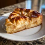 A close-up slice of an amazing apple tart showing caramelized apples and creamy filling on a white plate.