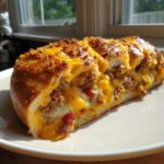 A cross-section of homemade garbage bread stuffed with ground meat and melted cheddar cheese.