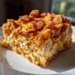 A close-up slice of amazing hot chicken salad casserole with a creamy interior and crunchy, golden cornflake topping.
