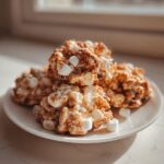 A stack of gooey, caramel-colored avalanche cookies studded with mini marshmallows on a white plate.