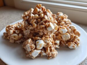 A stack of gooey, caramel-colored avalanche cookies studded with white marshmallows on a white plate.