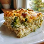 A close-up serving of creamy chicken broccoli rice casserole topped with melted, browned cheese.