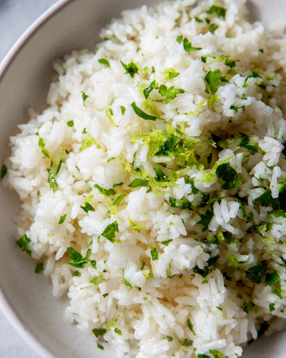 Close-up of fluffy white cilantro lime rice topped with chopped cilantro and bright green lime zest.