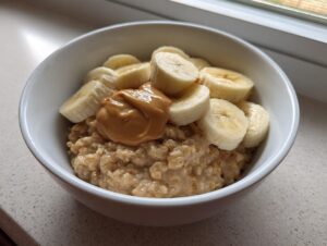 Close-up of creamy banana oatmeal topped with sliced bananas and a dollop of peanut butter.