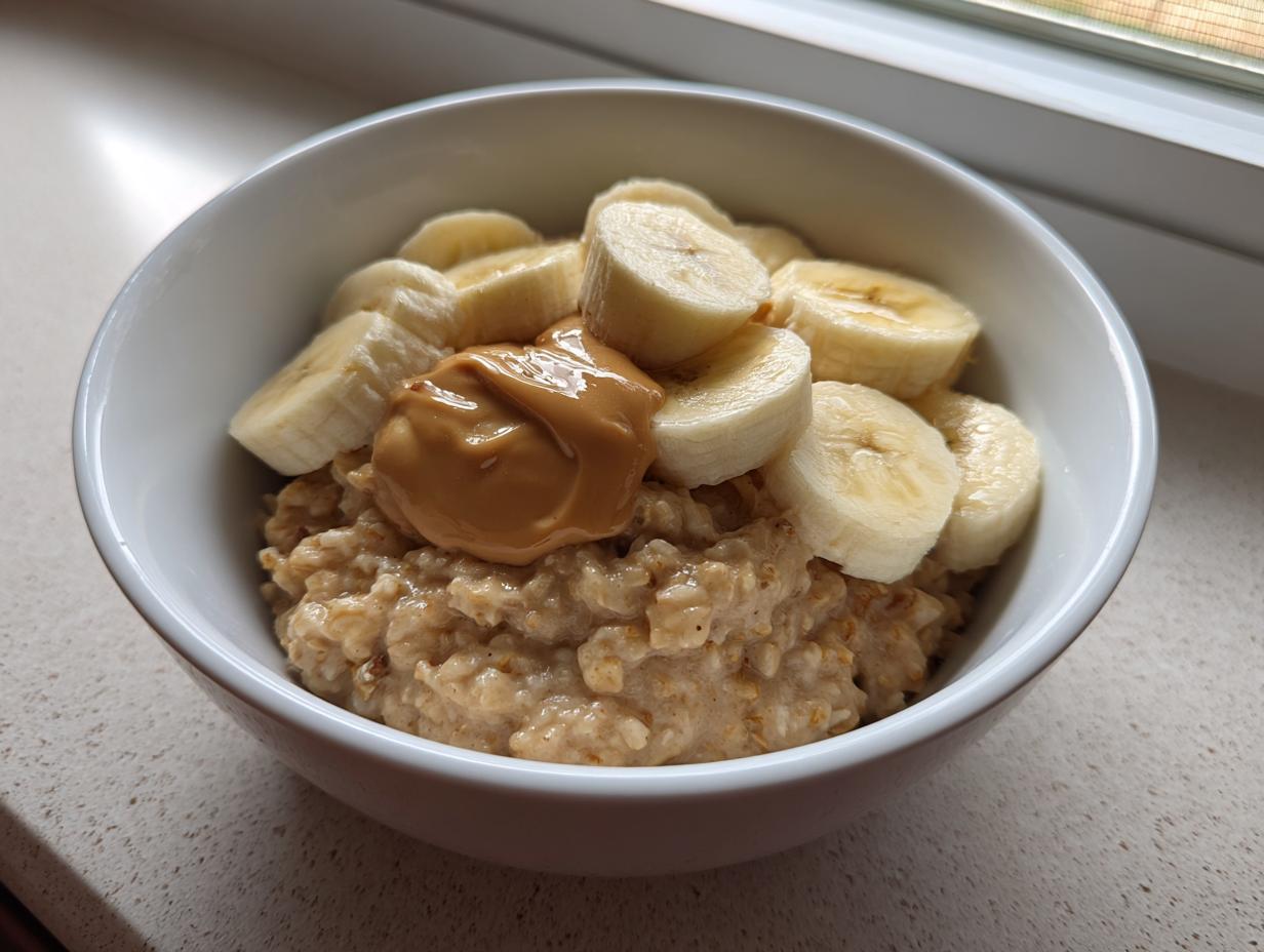 Close-up of creamy banana oatmeal topped with sliced bananas and a dollop of peanut butter.