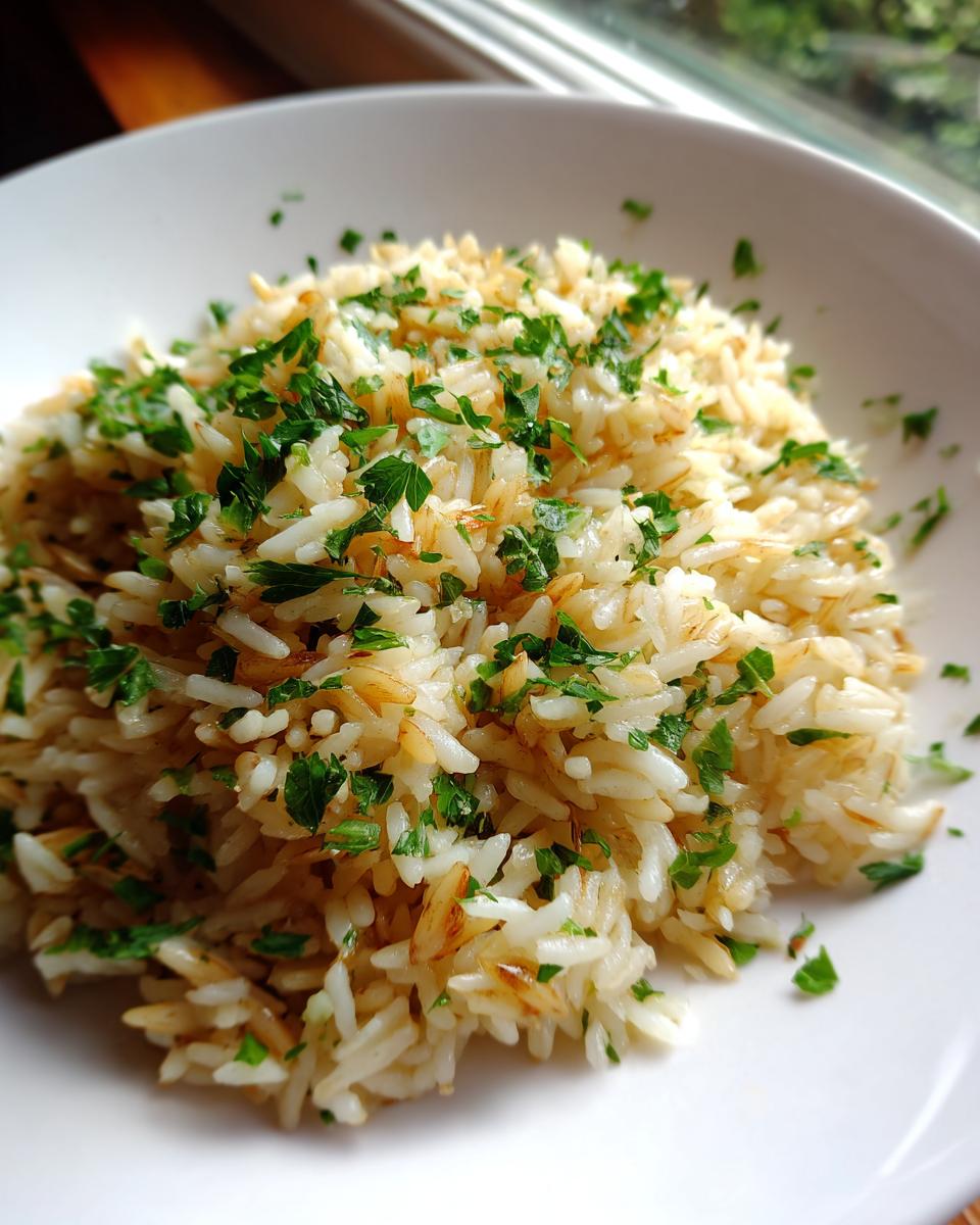 Close-up of fluffy rice pilaf mixed with toasted vermicelli and topped with fresh chopped parsley.