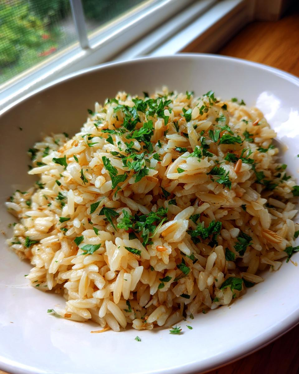A close-up of fluffy rice pilaf mixed with toasted vermicelli and topped with fresh parsley.