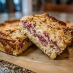 Close-up of two slices of homemade reuben bake showing layers of corned beef, cheese, and bread base.