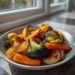 A close-up of perfectly cooked roasted vegetables, including charred broccoli, bright orange carrots, and sweet onions.