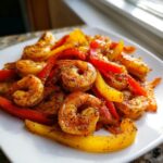 Close-up of perfectly cooked shrimp fajitas, featuring seasoned shrimp mixed with vibrant red and yellow bell pepper strips.