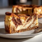 A close-up of a rich slice of snickerdoodle cheesecake showing a beautiful cinnamon swirl pattern.