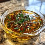 Close-up of flavorful olive oil bread dip seasoned with red pepper flakes and fresh parsley.